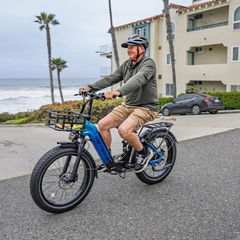 Man riding a blue Heybike Horizon electric bike on a coastal road.