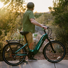 Rider standing with a green Heybike Hybrid electric bike at sunset.