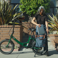 Rider loading a bag onto the green Blix Vika X Folding eBike rear rack