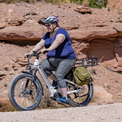 Woman riding a white Heybike Alpha electric bike through rocky terrain.