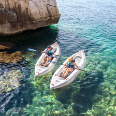 Aqua Marina Halve 13'1" Packayak on clear water with paddlers near rocky shoreline