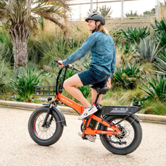 Woman riding an orange Heybike Mars 2.0 folding electric bike outdoors.