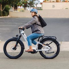 Woman riding a white Heybike Alpha electric bike on a paved road.
