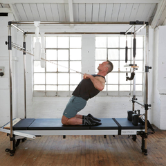 Align-Pilates Full Cadillac Frame (for A & C Series) in use for kneeling resistance exercise with straps on reformer