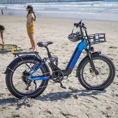 Blue Heybike Horizon electric bike with a front basket displayed on a beach.
