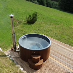 Hot tub on a wooden deck with a grassy hill and trees in the background