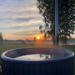 Hot tub with a scenic sunset over a field and trees in the background